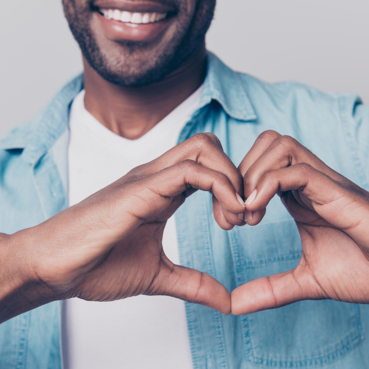 A Black man holding his hands together in a heart shape